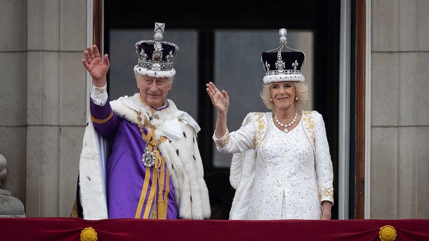 King Charles and Queen Camilla waving on the balcony of Buckingham Palace after being crowned.