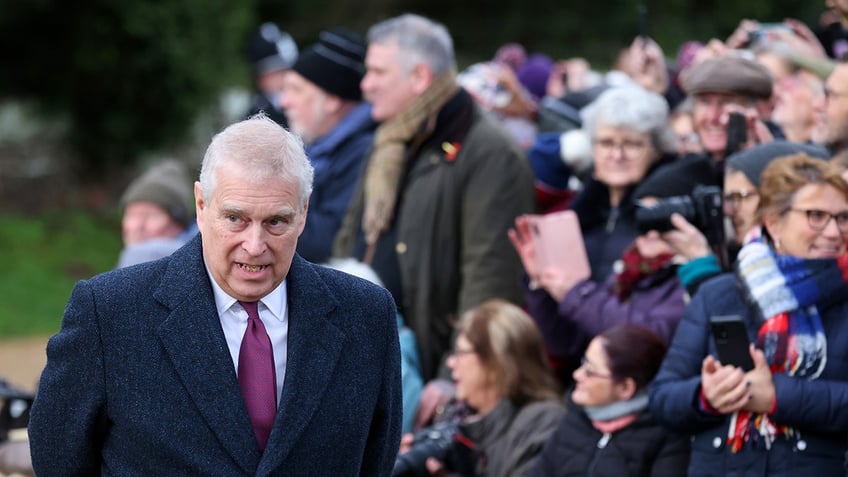 Prince Andrew walking away from a crowd of people.