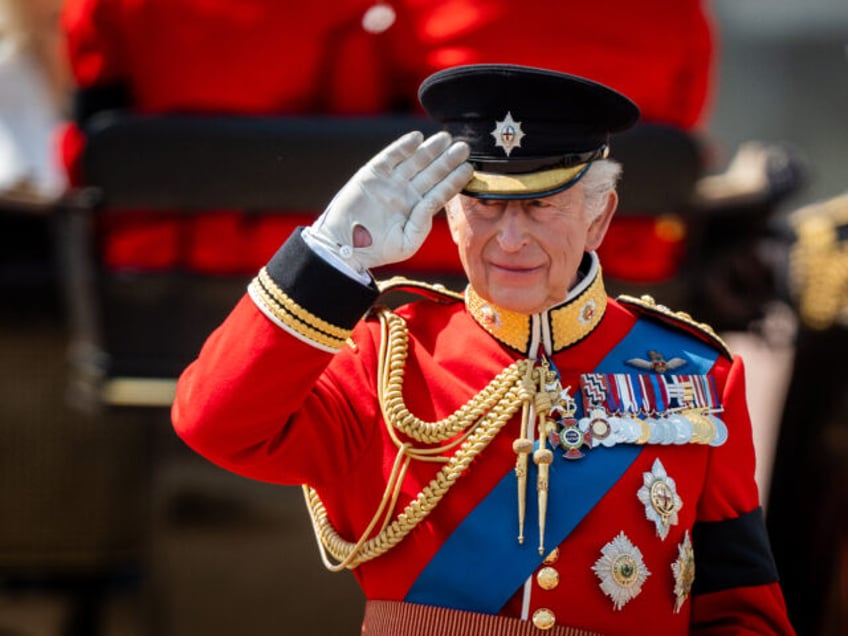 King Charles III gives a salute as he watches the parade march past after arriving back at