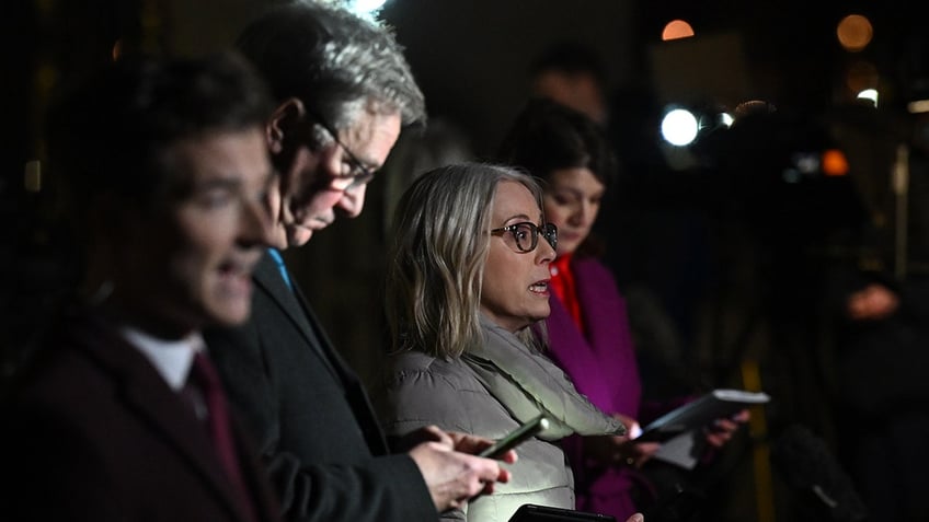 A crowd of people looking concerned and holding their phones