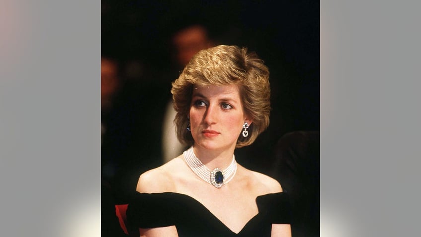 A close-up of Princess Diana wearing an off the shoulder black dress with jewels.