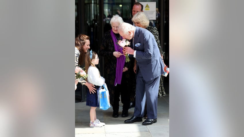 King Charles smelling flowers given to him by a little girl