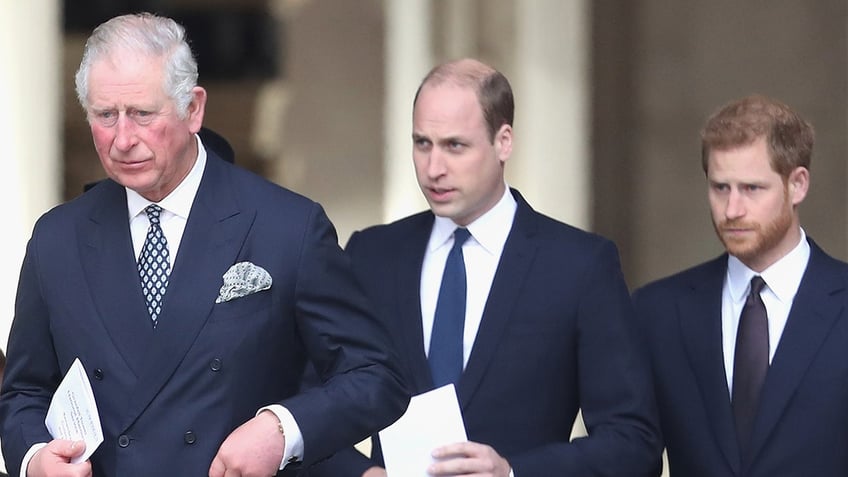 King Charles, Prince William and Prince Harry walking together in matching navy suits