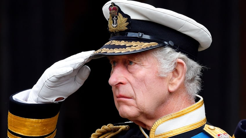 A close-up of King Charles doing the salute