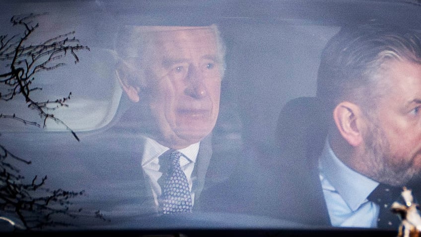 A close-up of a somber looking King Charles inside a car