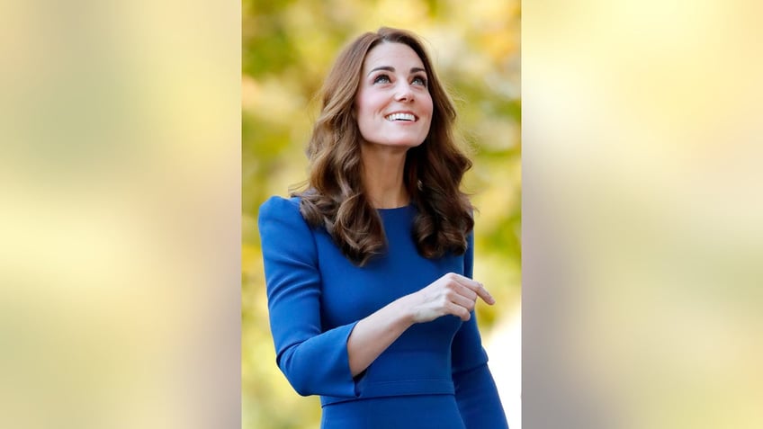 Kate Middleton wearing a blue dress smiling and looking up.