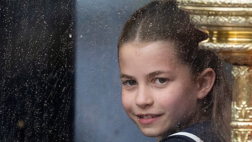 Princess Charlotte smiles in a navy dress at the Trooping the Colour ceremony inside her carriage