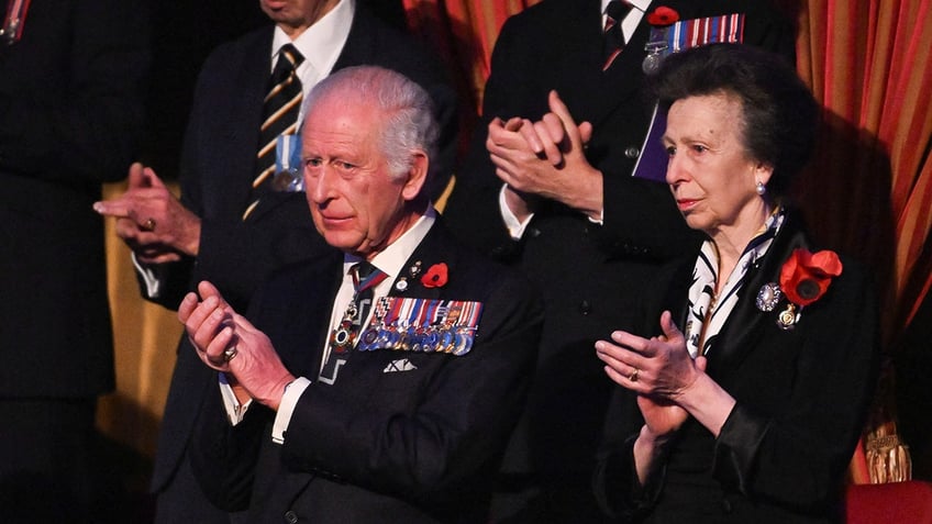 Princess Anne applauding in an audience next to King Charles.