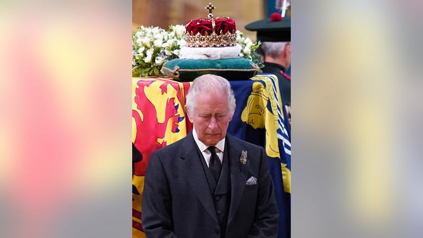 King Charles looking sad with a crown above his head on top of Queen Elizabeths coffin.