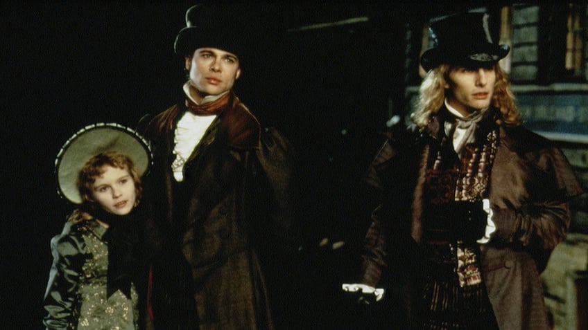 Kirsten Dunst as Claudia is held onto by Brad Pitt as Louis de Pointe du Lac in "Interview with a Vampire" who stands next to Tom Cruise as Lestat de Lioncourt