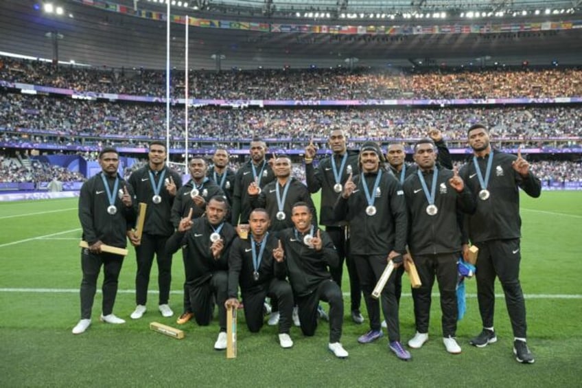 The Fiji team celebrate with their silver medals at the Stade de France following defeat t