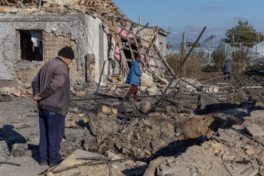 A local resident inspects a crater in the courtyard of a destroyed building following a mi