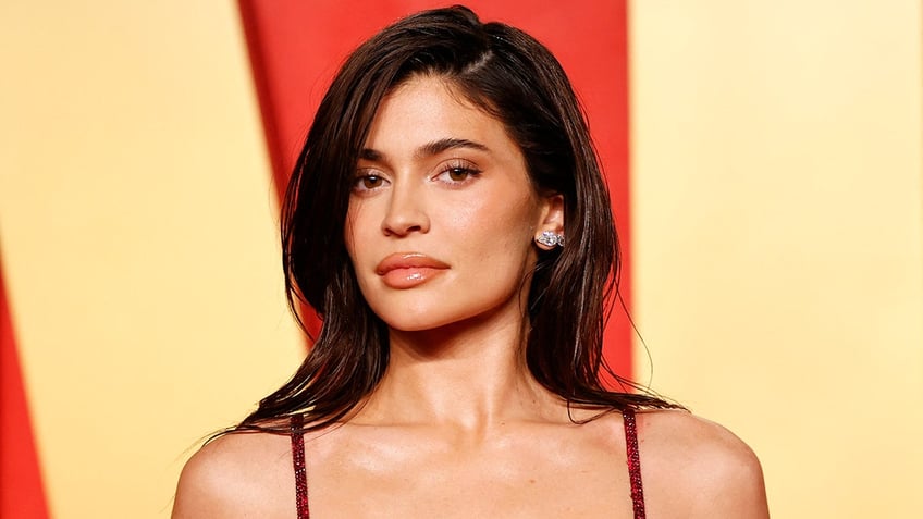 Kylie Jenner in a red strap dress at the Vanity Fair Oscar party looking directly at the camera 