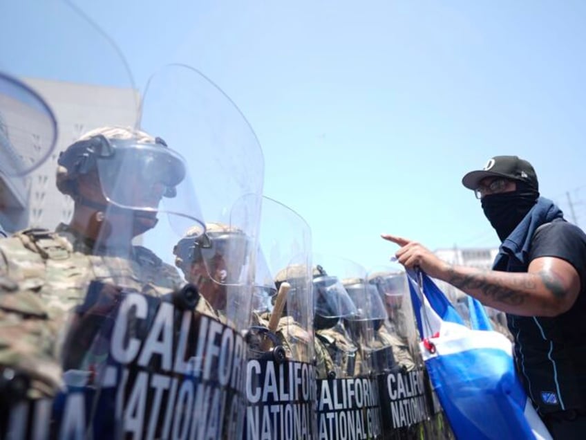 Un manifestante se enfrenta contra una fila de agentes de la Guardia Nacional de Estados U