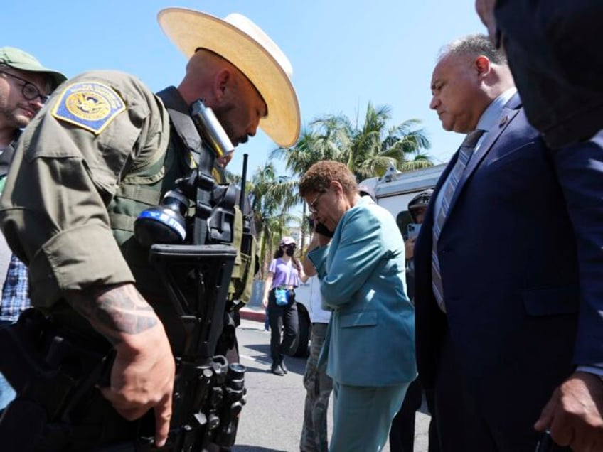 Los Angeles Mayor Karen Bass talks on her mobile phone next to a border patrol federal age