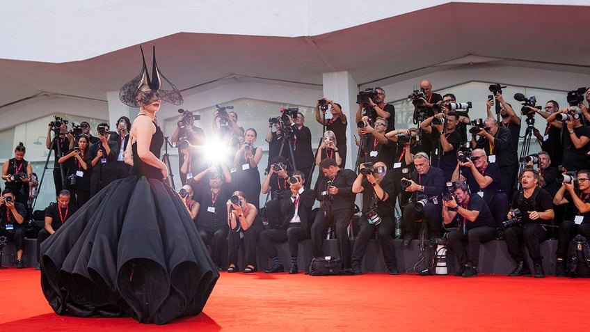 Actress Lady Gaga strikes a pose wearing a black ball gown.