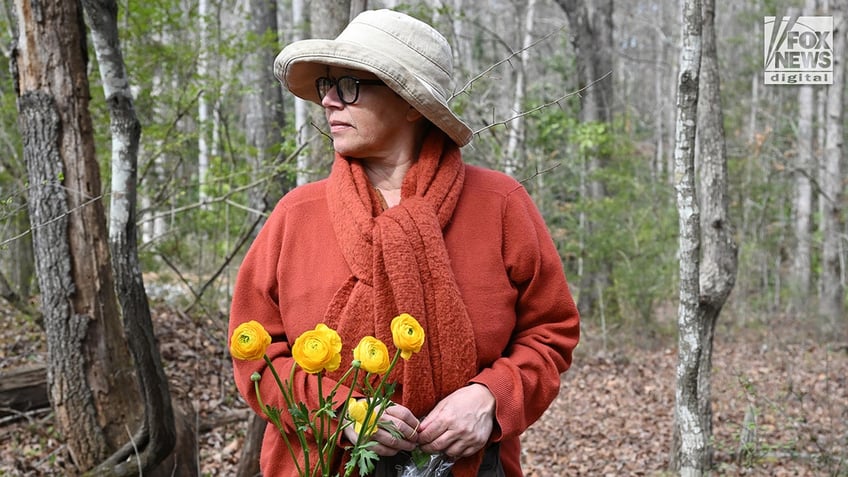 Cheri Smithson leaves flowers for Laken Riley along Lake Herrick