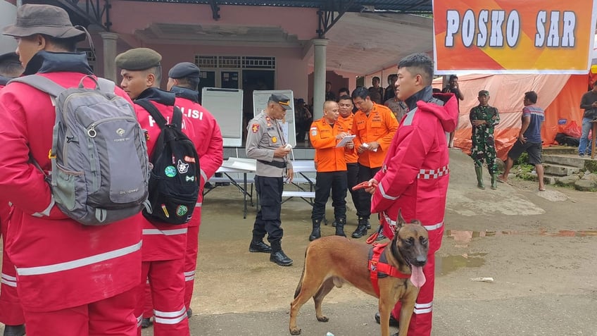 Workers dressed in the red uniforms of the Indonesian National Search and Rescue Agency prepare to head to the site of a deadly landslide.