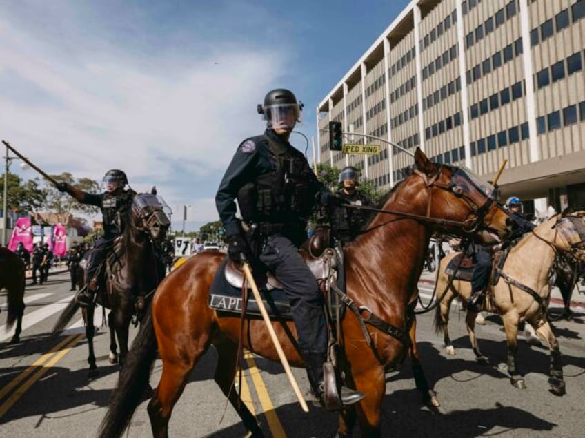 A mounted police officer grips a baton while patrolling the protest area in Los Angeles, C