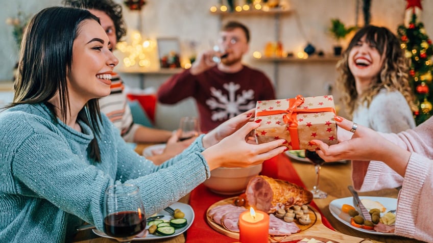 People exchange Christmas gifts over food.