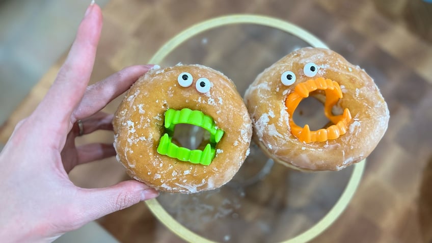 Mackenzie Biehl displays two of her "monster donuts" with vampire fangs.