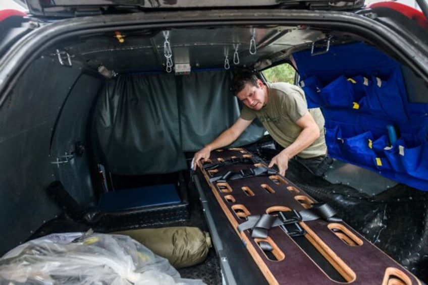 A Latvian volunteer helps convert a seized SUV into an armoured medevac transport for Ukra