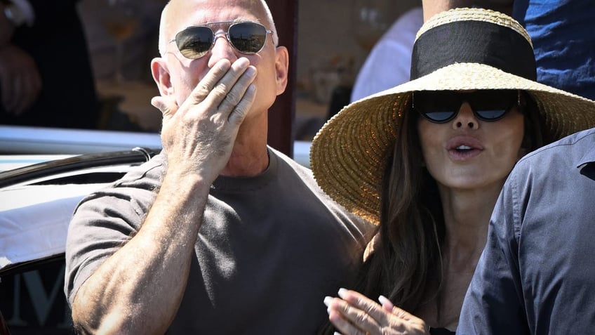 Jeff Bezos blows a kiss to the camera as he stands beside Lauren Sanchez