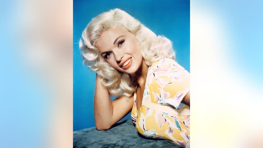Jayne Mansfield posing in a yellow and white floral dress.