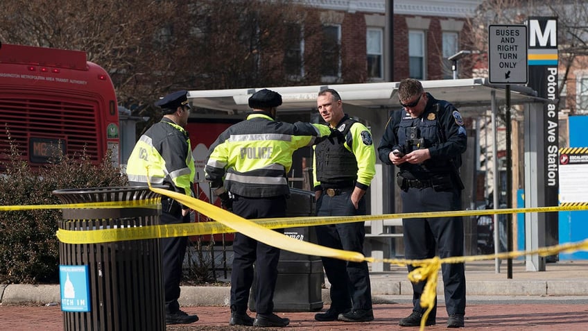 Police officers stand outside with caution tape around them