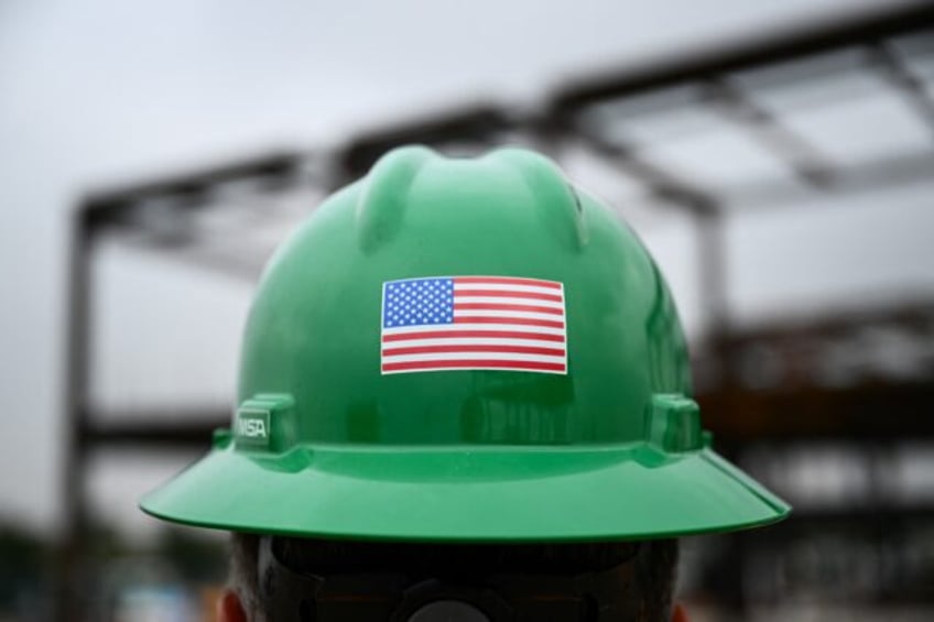 A US flag is displayed on a construction worker's safety helmet during a topping out