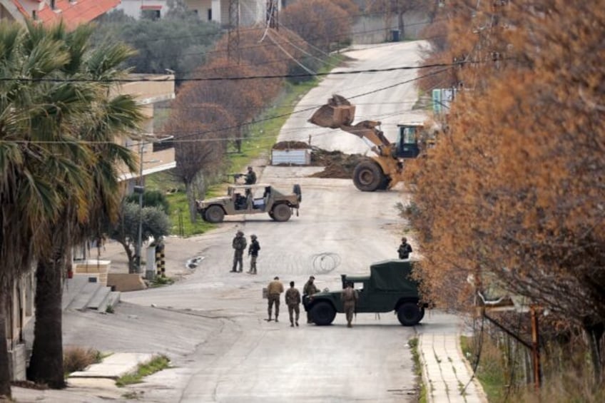 Lebanese army soldiers (R) and Israeli troops gather near their vehicles on either side of