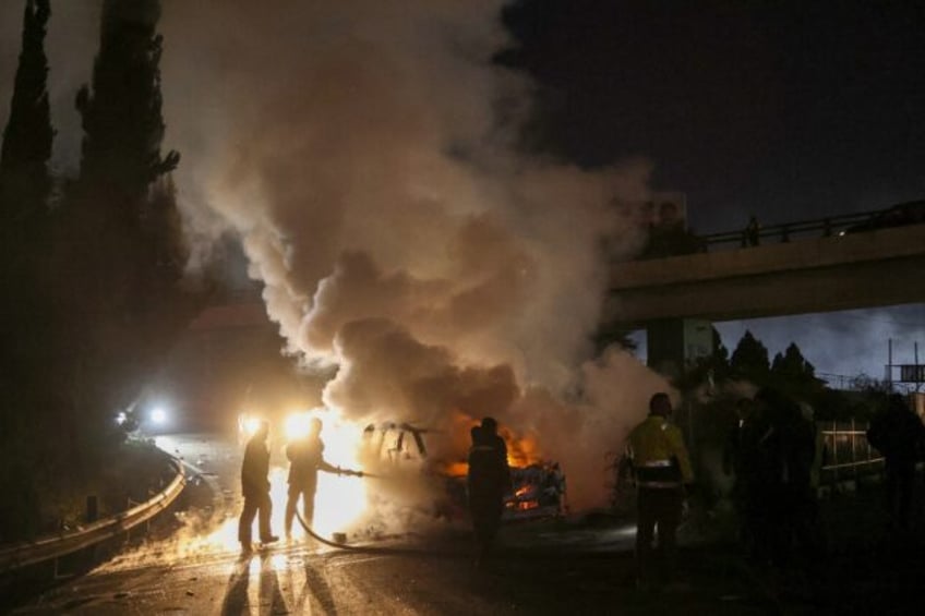 Firefighters extinguish a burning UNIFIL vehicle on the road leading to Beirut's internati