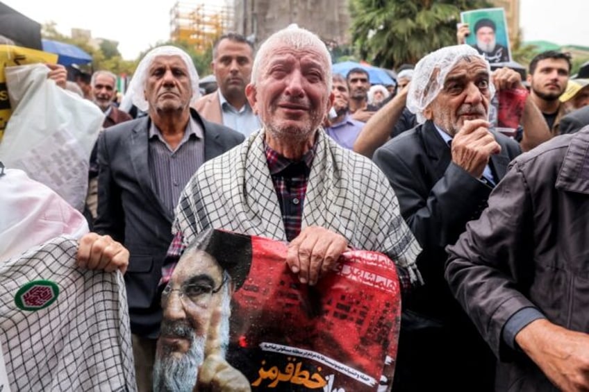 A man reacts as he holds a poster reading "crossing a red line" in Persian next to an imag