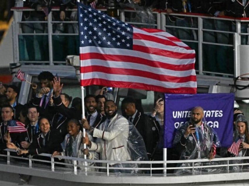 US' flag bearer LeBron James reacts as he stands with other members of his delegation