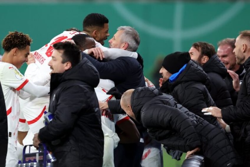 RB Leipzig coach Marco Rose is embraced by his players after Lois Openda's second goal