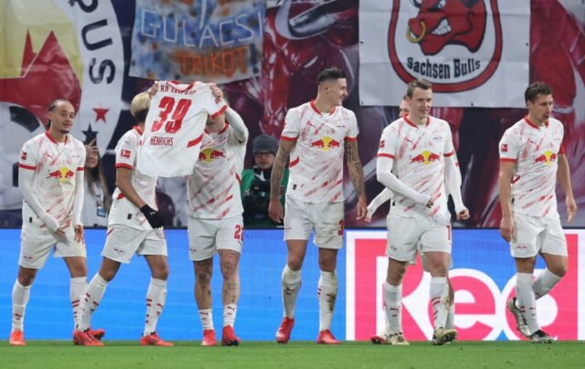 RB Leipzig players hold up Benjamin Henrichs' jersey in support of the injured defender