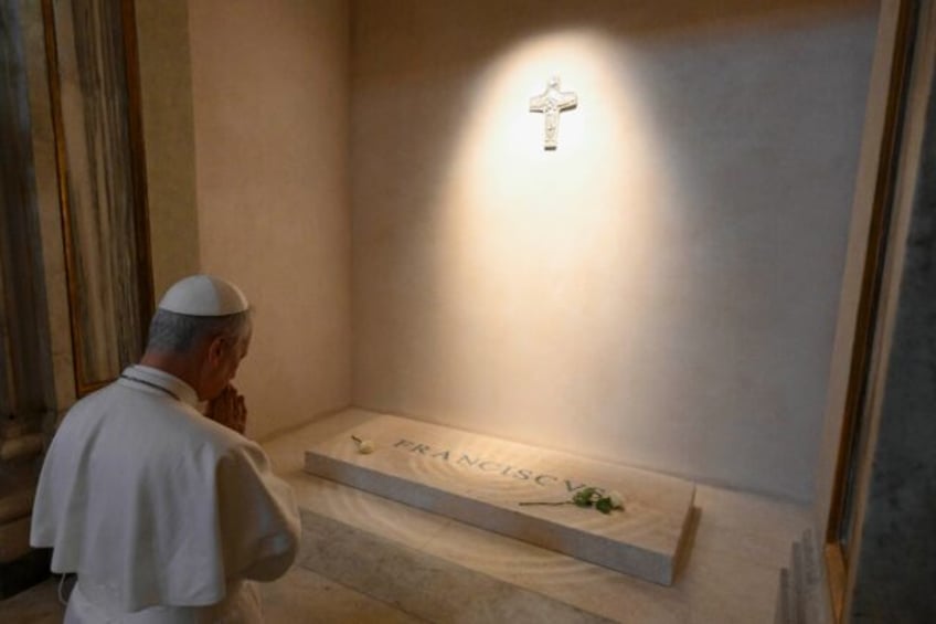 Vatican News published a photo of the white-robed pope kneeling before Francis's simple ma