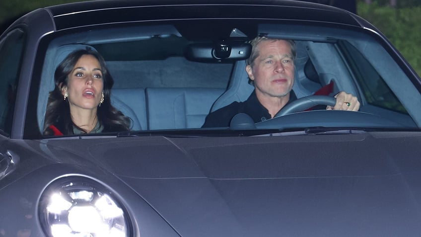 Brad Pitt driving his Porsche wears a black shirt drives up to Leonardo DiCaprio's 50th birthday with girlfriend Ines de Ramon with her mouth ajar