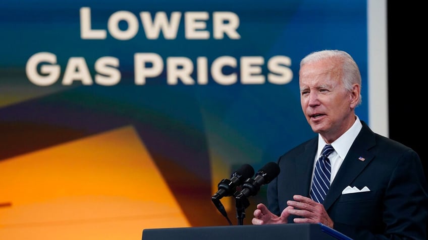 President Biden speaking with "lower gas prices" sign over his right shoulder