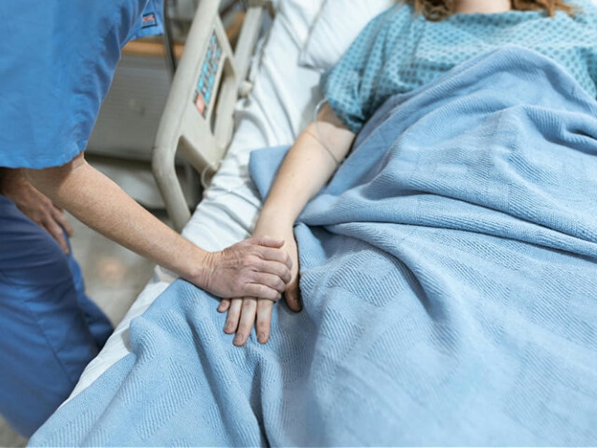 Person in Blue Scrub Suit Holding the Hand of a Patient