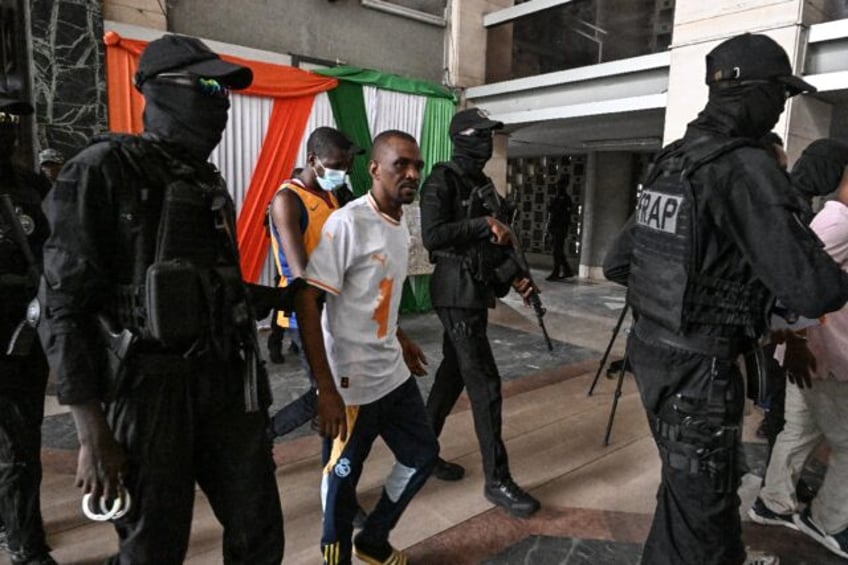 Police in Ivory Coast escort the accused after their life terms were confirmed for complic