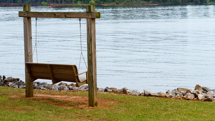 wooden swing next to lake murray on overcast day