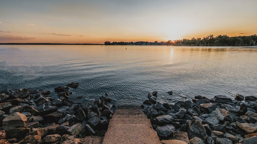 concrete steps lead into lake murray while sun sets over water