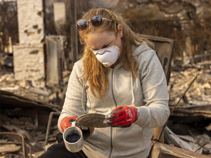 A woman looks at items found in her parent's home destroyed by the Palisades Fire in