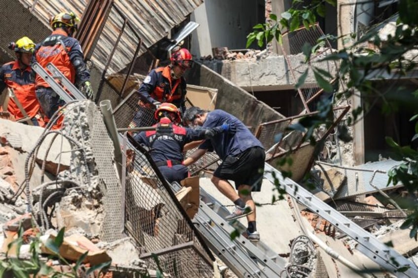 Emergency workers assisted a survivor after he was rescued from a damaged building in New