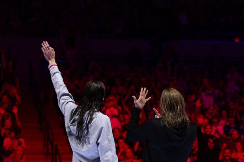 Kate Douglass waves to the crowd as Lilly King of the United States shows off her engageme