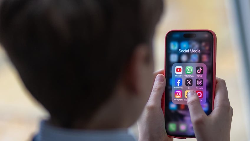 Kid holds phone with social media icons on screen