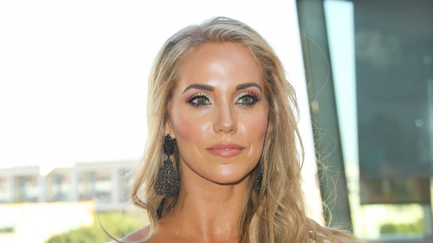 Elizabeth Berkley in a white plunging top looks serious on the carpet