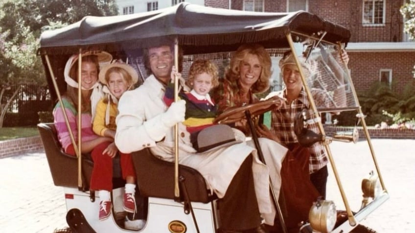 Michael Landon riding a golf cart with his family