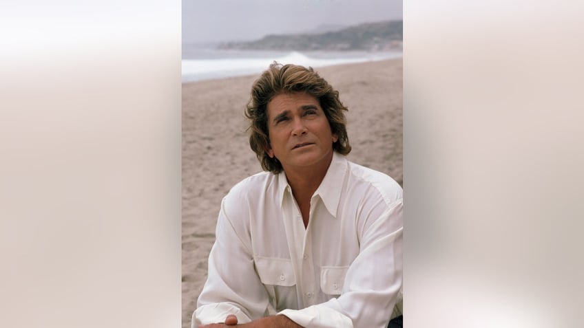 Michael Landon looking up at the sky wearing a white shirt.